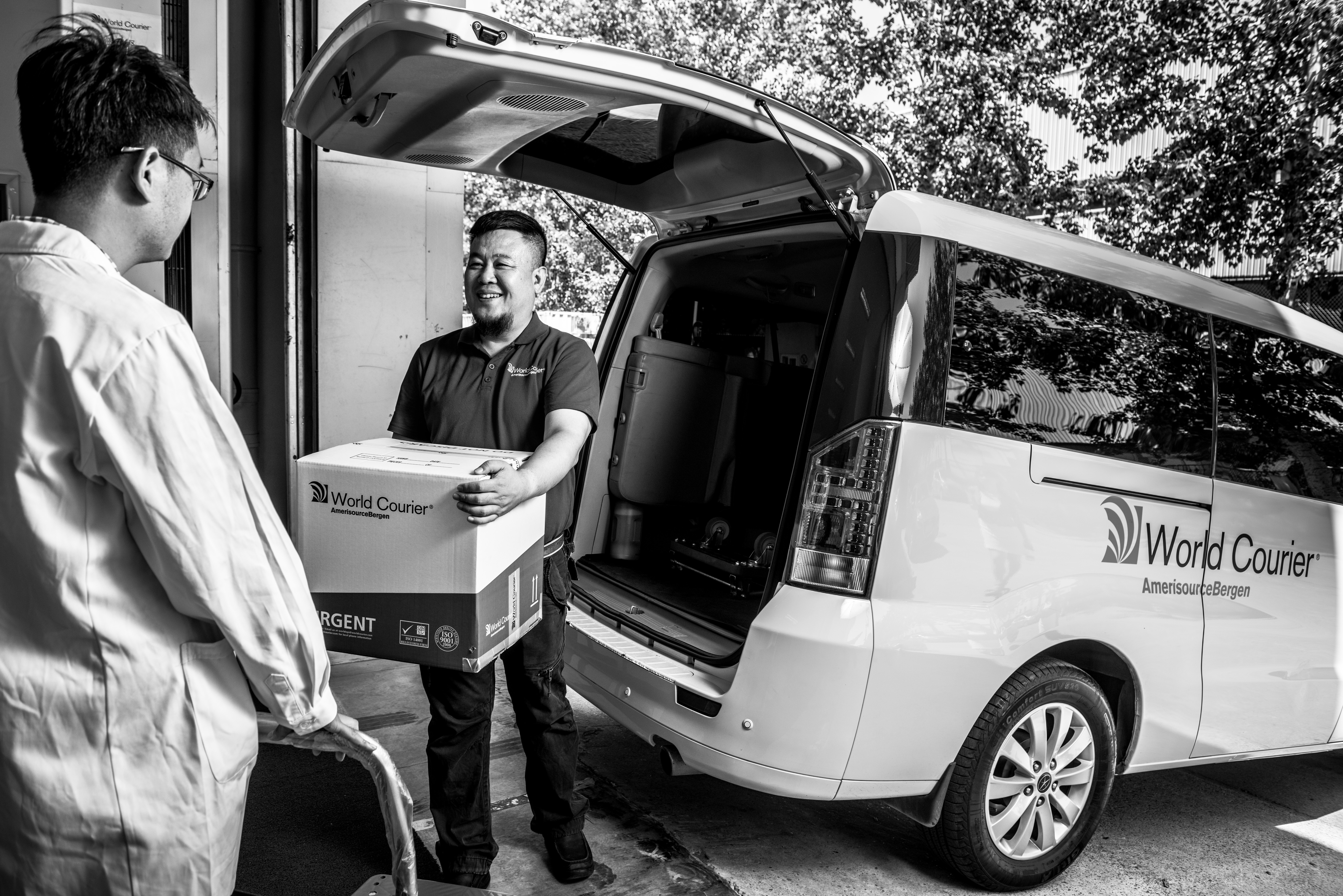 A World Courier driver delivers a temperature-controlled shipment to a man in a lab coat.