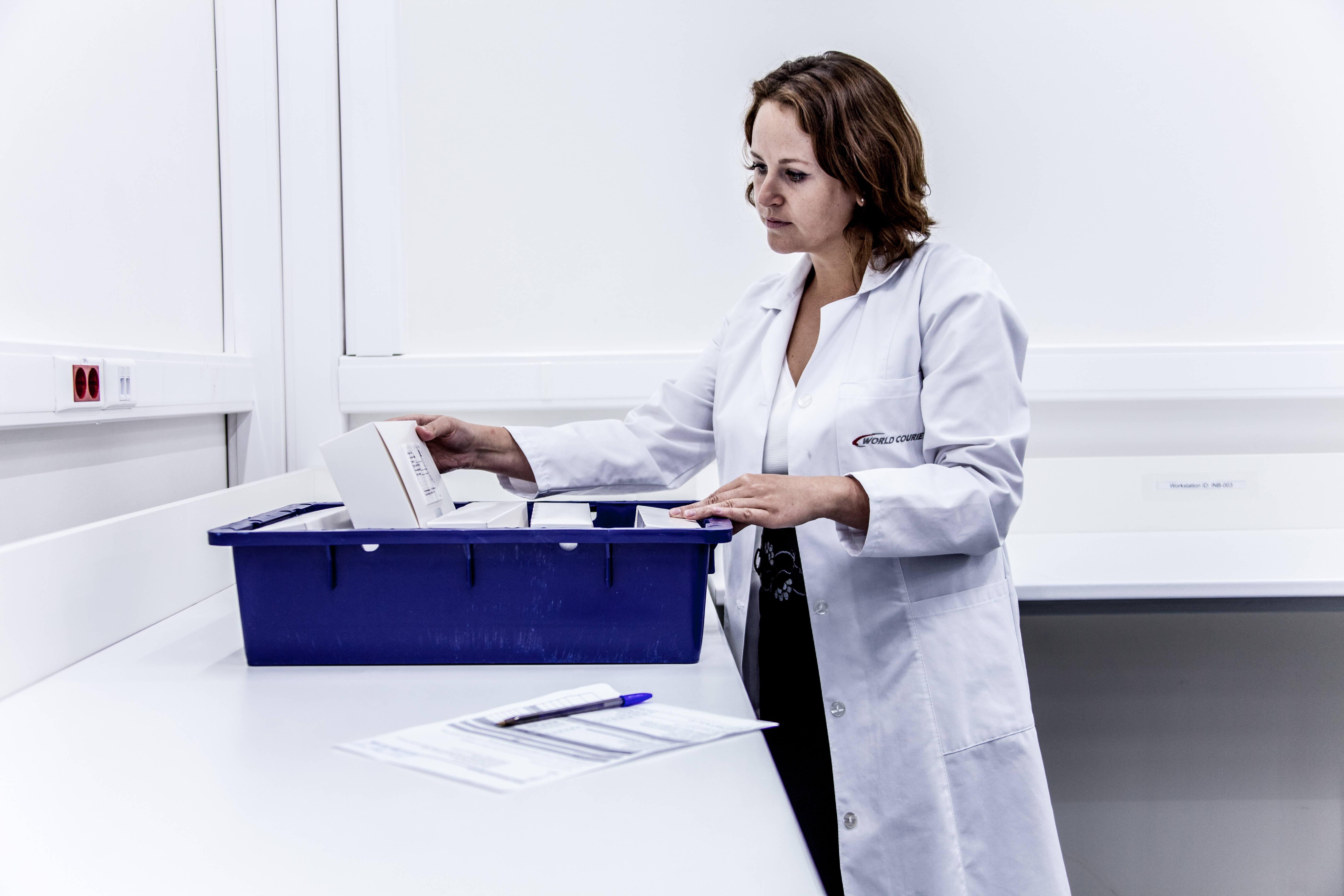 A woman in a lab coat looking at storage container with medication in it.
